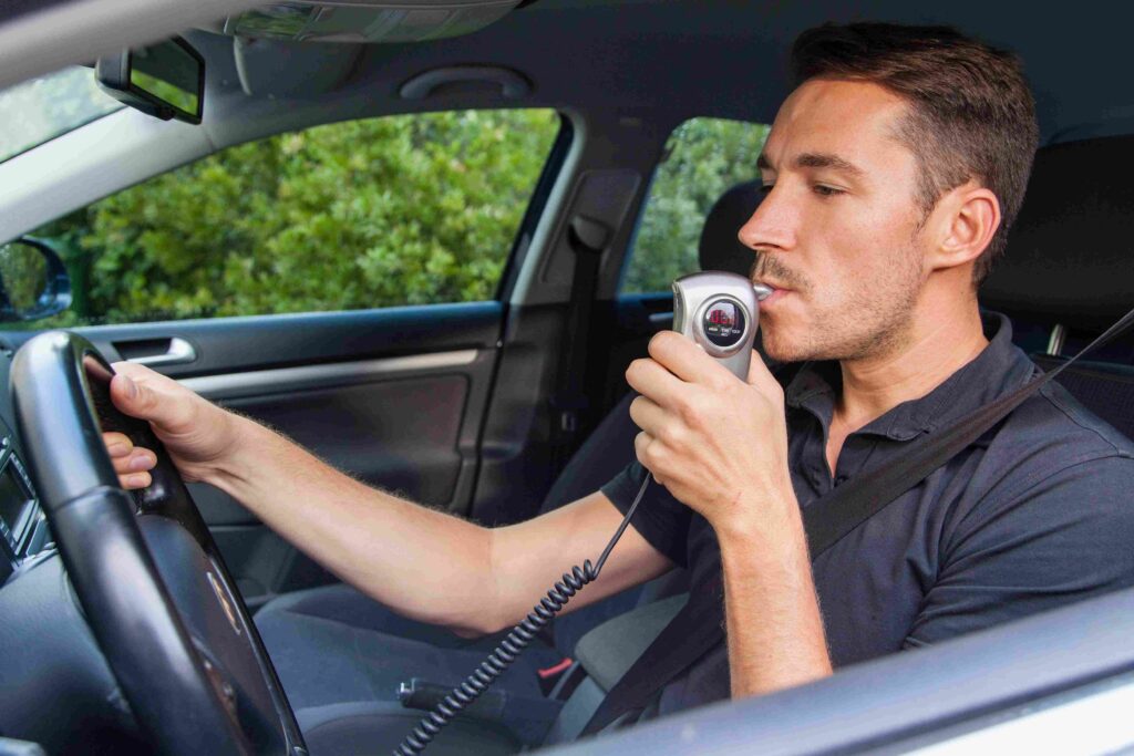 Un homme dans une voiture qui fait un Ethylotest anti-démarrage