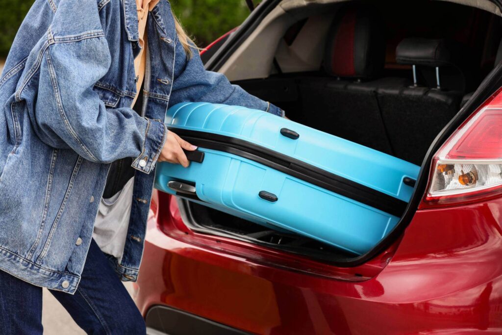 Une femme qui charge une valise dans le coffre de sa voiture