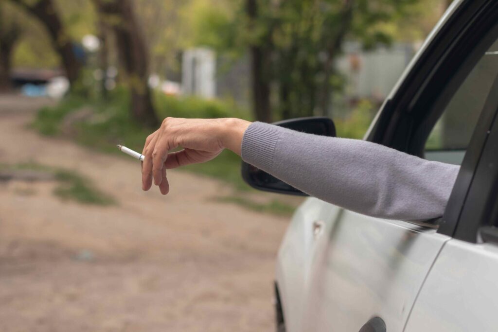 Une personne dans sa voiture tenant une cigarette dans les mains